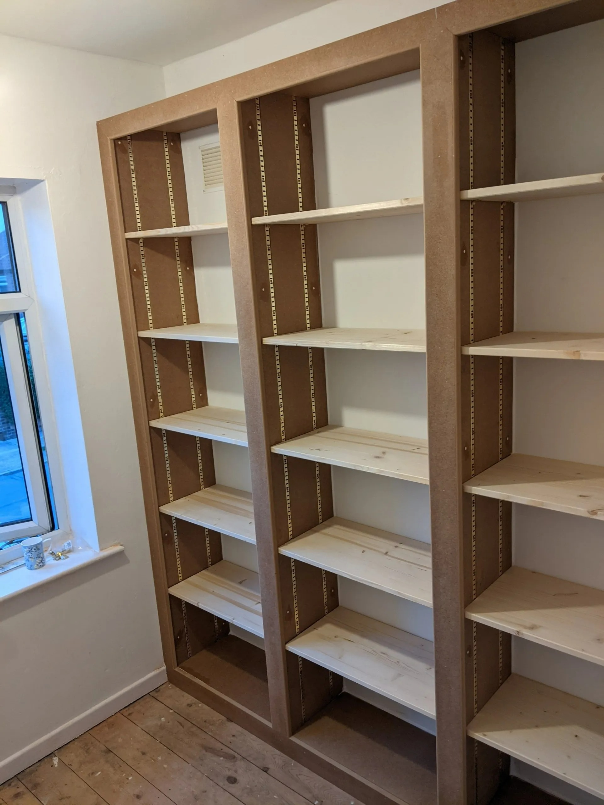 Custom wooden shelving unit in a room, showcasing craftsmanship in bespoke joinery and carpentry, designed for efficient storage solutions.